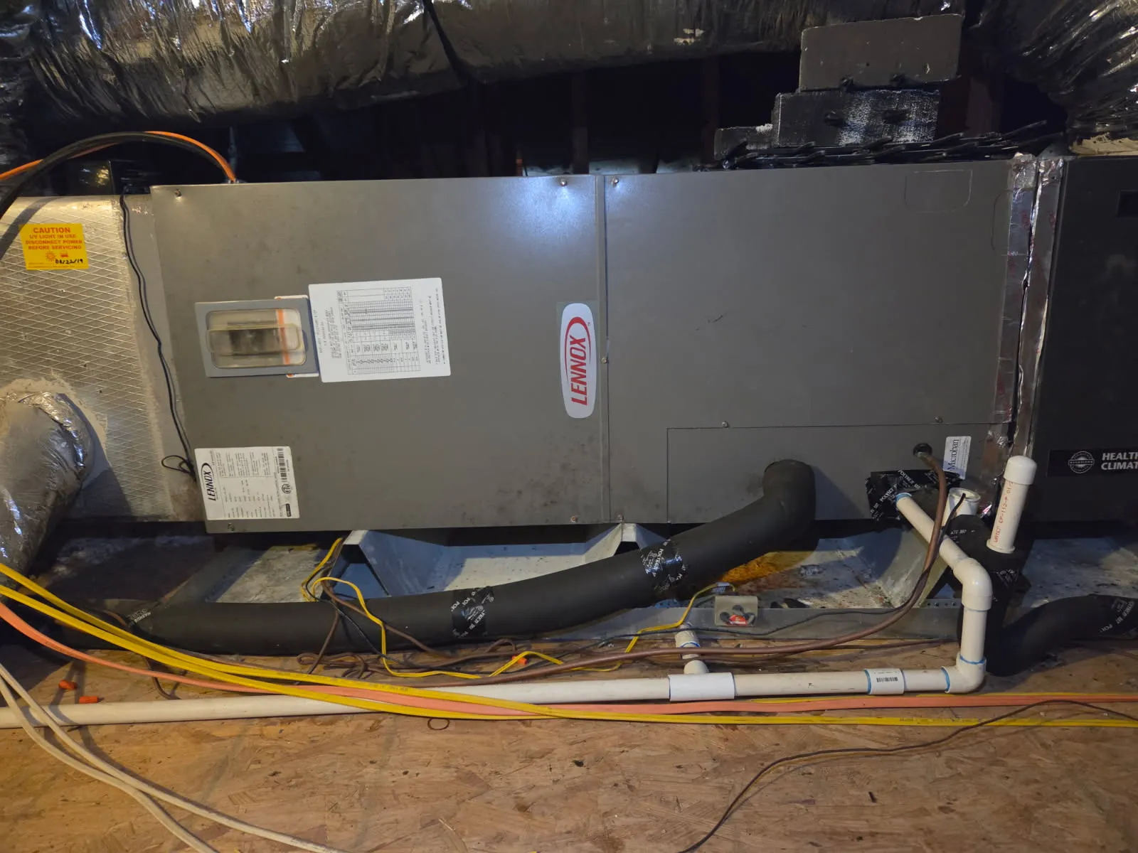 Before: aging Lennox attic air handler with messy line set and drain plumbing